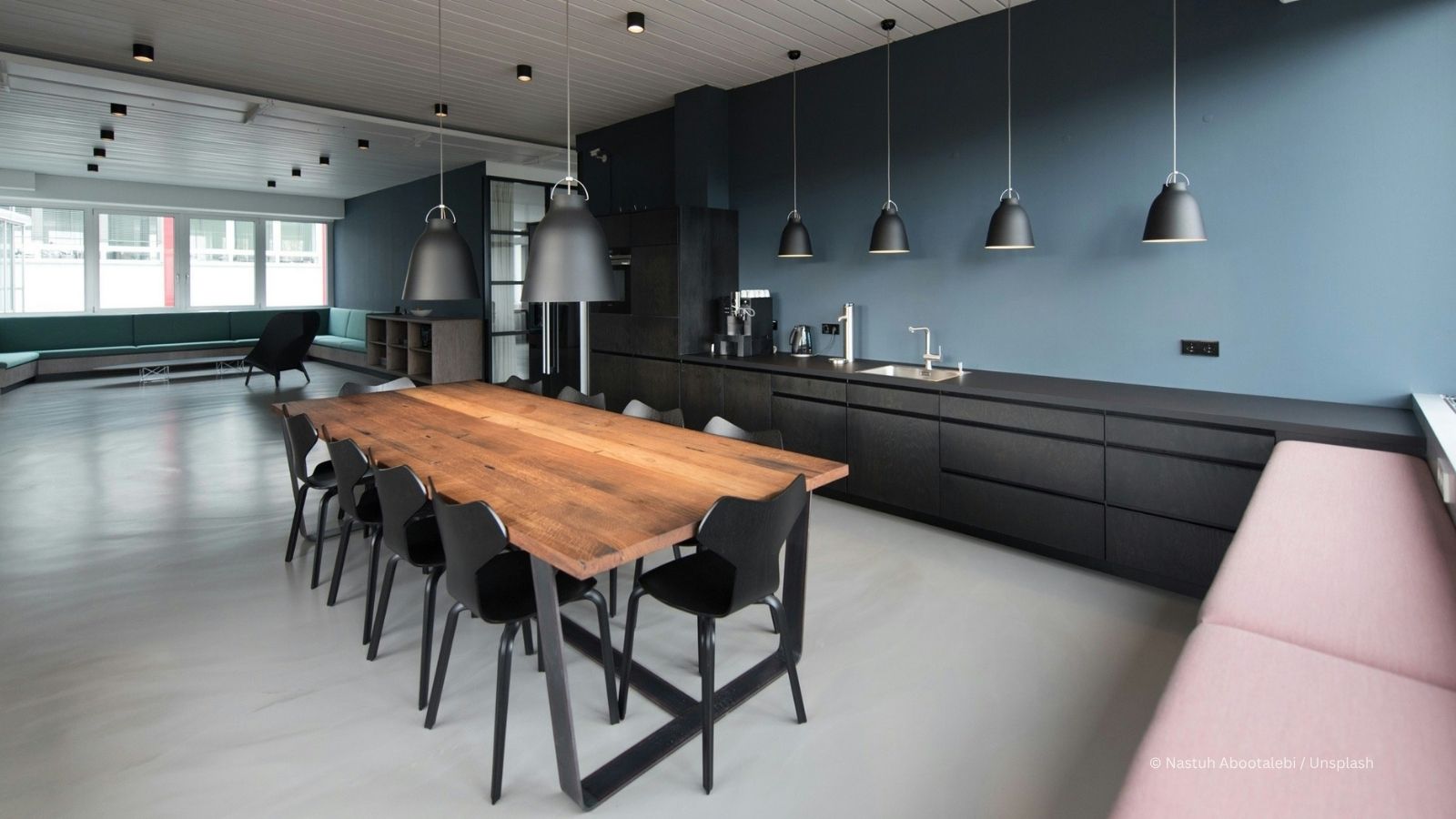 Hochwertiger Innenausbau und moderne Küchen-Sanierung in Hamburg mit großem Holztisch und dunkelblauer Wandgestaltung.